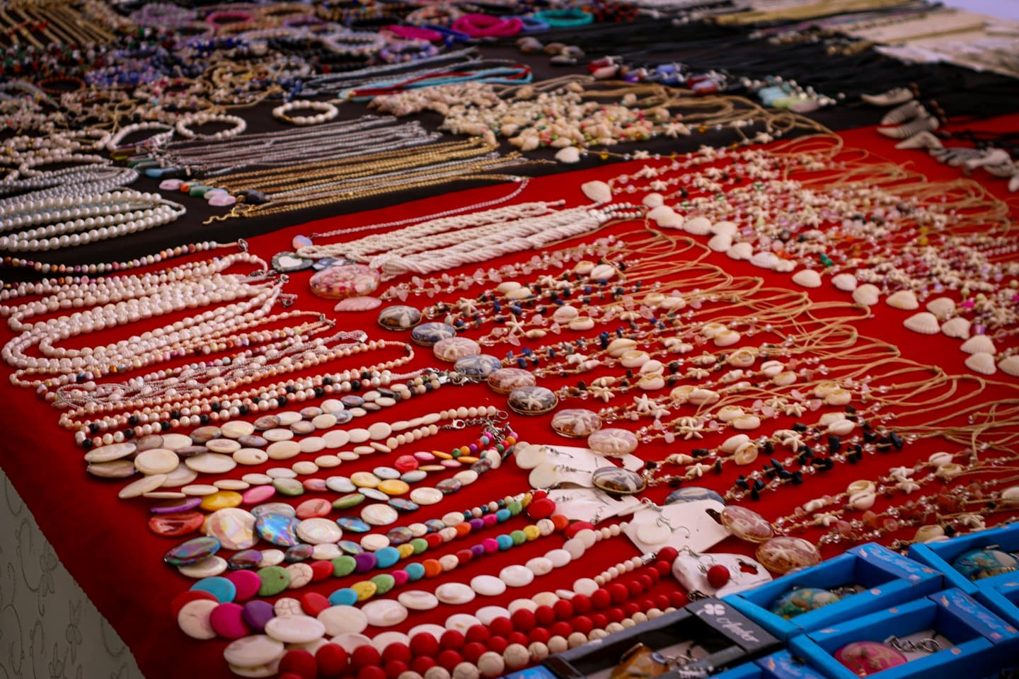 Handmade necklaces and bracelets displayed on a market stall table.