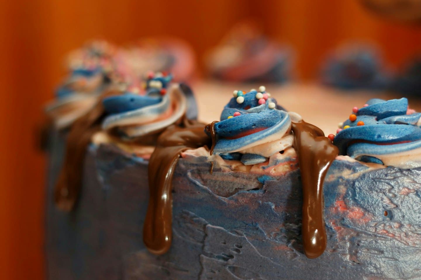Swirled frosting peaks and chocolate ganache decorate a festive cake.
