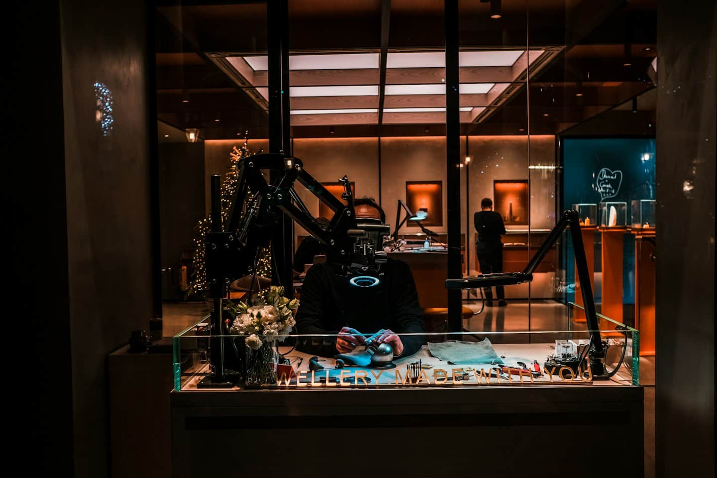 A jeweler works at a workbench inside a luxury shop.